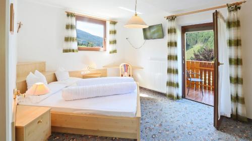 a bedroom with a large bed and a balcony at Pension Alpenhof B&B in Colle Isarco