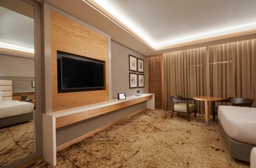 a hotel room with a television and a bed and a table at The Residency Towers Puducherry in Puducherry