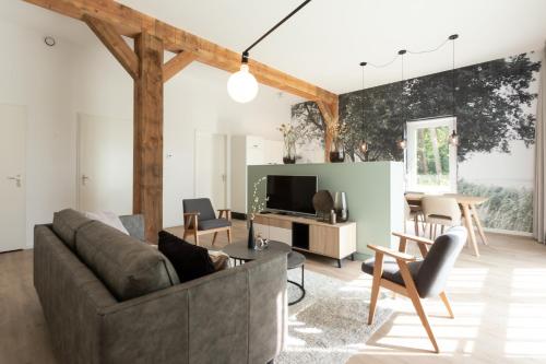 a living room with a couch and a tv at Hofstede Moesbosch I Kloeg Collection in Koudekerke