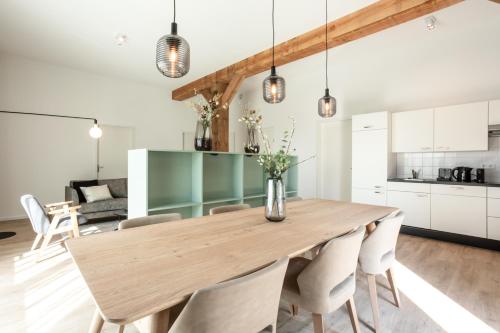 a kitchen and dining room with a wooden table and chairs at Hofstede Moesbosch I Kloeg Collection in Koudekerke