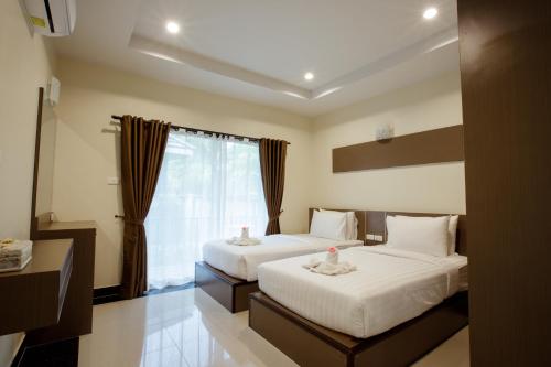 a hotel room with two beds and a window at Ioon Resort ไออุ่นรีสอร์ท in Sara Buri