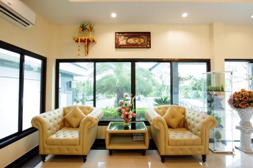 two chairs and a table in a room with windows at Ioon Resort ไออุ่นรีสอร์ท in Sara Buri