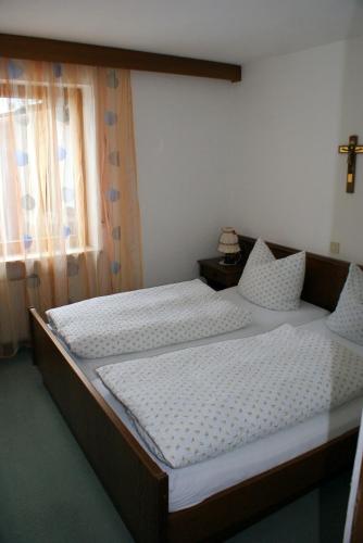 two beds in a bedroom with a cross on the window at Haus Sorgschrofen in Pfronten