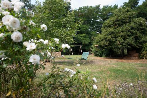 a green chair sitting in a yard with flowers at Les gîtes du Moulin castral in Geer