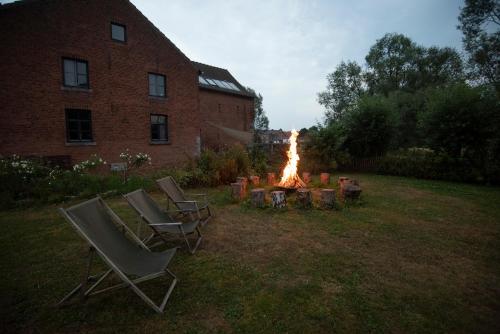 a fire pit in a yard next to a brick building at Les gîtes du Moulin castral in Geer