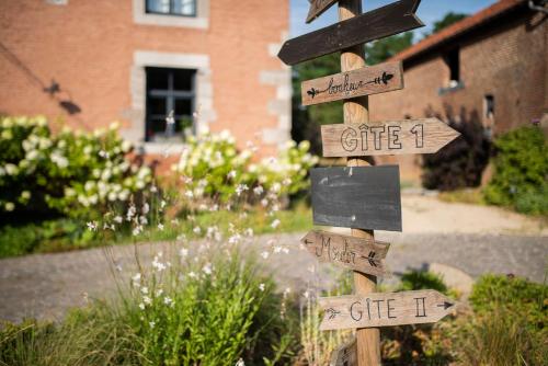 a wooden sign in a garden with signs that say gifts at Les gîtes du Moulin castral in Geer