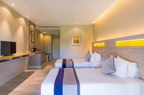 Habitación de hotel con 2 camas y TV de pantalla plana. en Chatrium Golf Resort Soi Dao Chanthaburi, en Ban Thap Sai