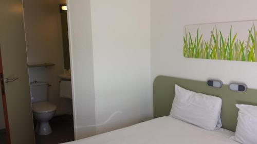 um quarto com uma cama, um WC e um espelho em Ibis Budget Marseille Valentine em Marselha