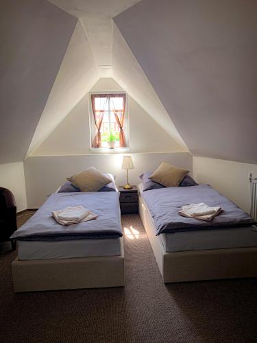 two beds in a attic room with a window at JP-KU ubytování Kadaň in Kadaň