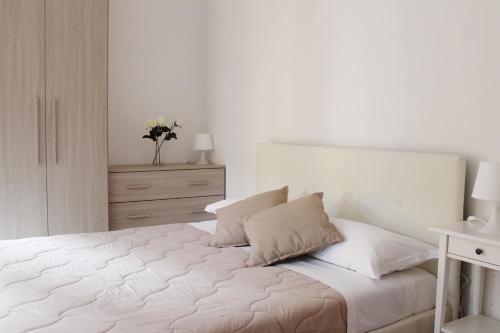 una camera da letto bianca con un letto con lenzuola e cuscini bianchi di APPARTAMENTO ROSE E TULIPANI 3 a Negrar