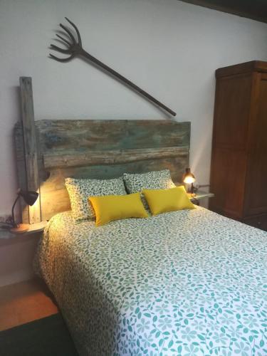 a bedroom with a bed with a wooden headboard and yellow pillows at Alberg Rural La Rectoria de Pedra in Bellver de Cerdanya 