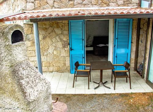 a table and chairs on a patio with blue shutters at Résidence de Filitosa - Le Torréen in Sollacaro
