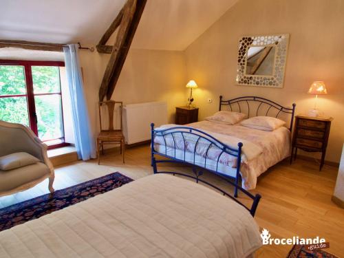 a bedroom with two beds and a chair and a mirror at Chambres d'Hôtes Logis de l'Etang de l'Aune in Iffendic