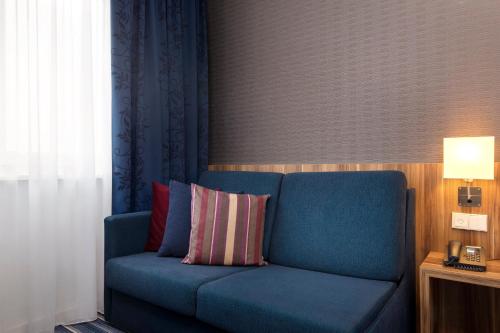 a blue couch with a pillow in a room at Holiday Inn Express Bremen Airport by IHG in Bremen