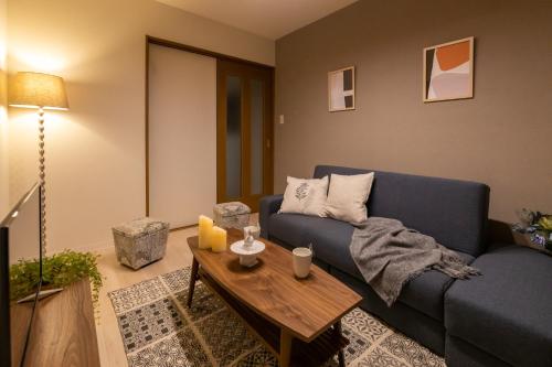 a living room with a blue couch and a table at AGURIHOME Hayashiji in Osaka