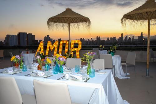 a table with white tables and chairs and umbrellas at Hotel Deloix 4* Sup in Benidorm
