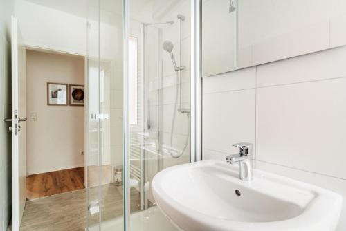 La salle de bains blanche est pourvue d'un lavabo et d'une douche. dans l'établissement Bode_Apartments, à Elend