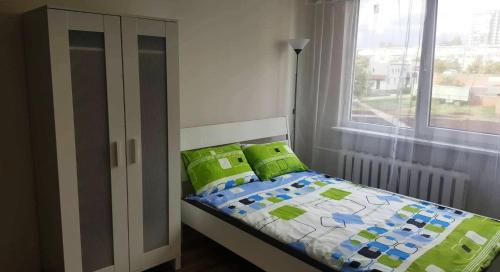 ein Schlafzimmer mit einem Bett mit grünen Kissen und einem Fenster in der Unterkunft Apartment for You in Klaipėda