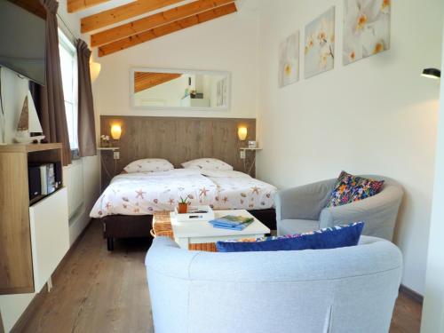 een slaapkamer met een bed, een bank en een stoel bij DO27 Charmante Studio in Domburg in Domburg