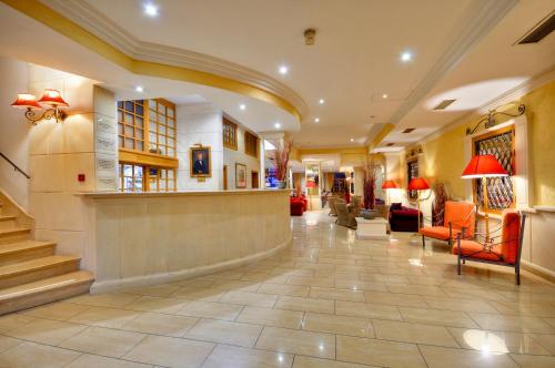 a lobby of a hotel with orange chairs and stairs at Hotel Kennedy Nova in Il-Gżira