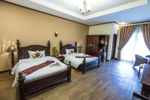 a bedroom with two beds and a living room at Bali Hotel in Phnom Penh
