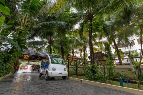 a small white car parked in a courtyard with palm trees at Bali Hotel in Phnom Penh