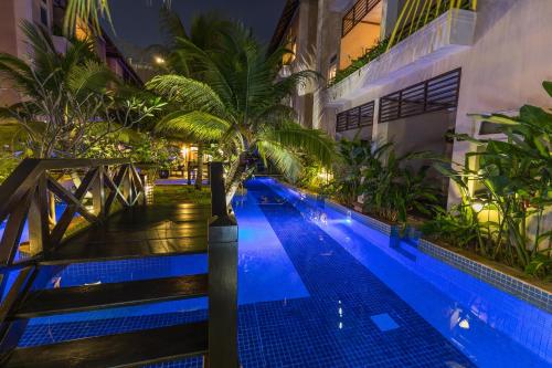 a swimming pool with a palm tree next to a building at Bali Hotel in Phnom Penh