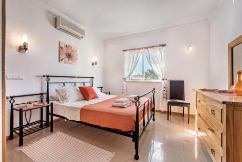 a bedroom with a bed with orange sheets and a window at Apartment Galé Garden 1A in Albufeira