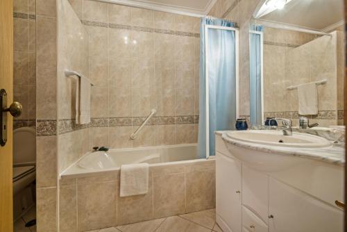 a bathroom with a tub and a sink and a bath tub at Apartment O Monte C in Albufeira