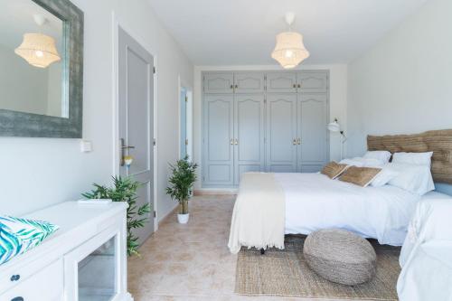 a white bedroom with two beds and a mirror at La Llevantina Boutique Villa in Calonge