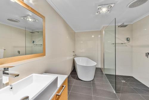 a bathroom with a tub and a sink and a mirror at Southgate Motel in Mount Gambier