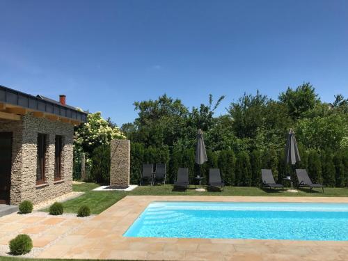 a pool with chairs and umbrellas in a yard at Villa Aruba & Private SPA Suites in Keszthely