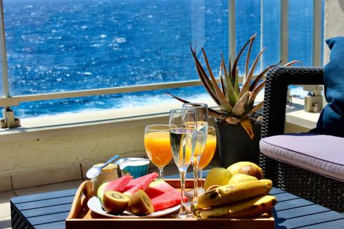 una mesa con una bandeja de fruta y copas de vino en Ocean View Apartment, en Porís de Abona