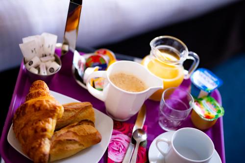 une table avec une assiette de nourriture et une tasse de café dans l'établissement Logis Hotel Du Chateau, à Caen