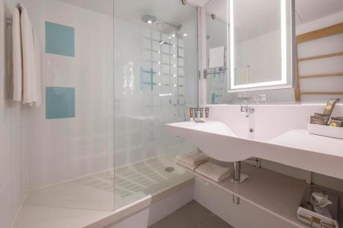 a white bathroom with a sink and a shower at Novotel York Centre in York