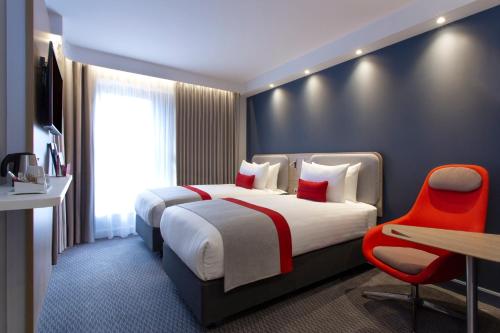 a hotel room with a large bed and a desk and chair at Holiday Inn Express Royal Docks by IHG in London