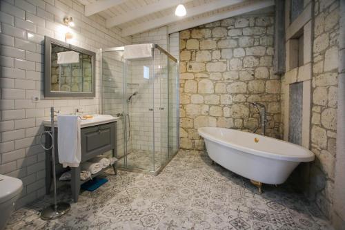 a bathroom with a tub and a shower and a sink at Cadde 75 Luxury Hotel - Alaçatı in Alaçatı