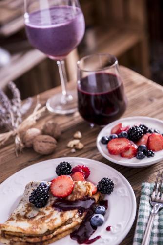a table with two plates of food and a glass of wine at Berry House in Vigolo Vattaro