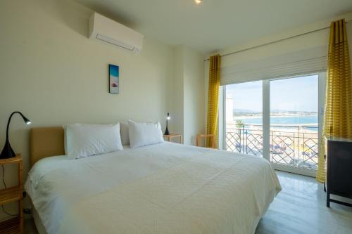 ラゴスにあるFábrica da Ribeira 80 by Destination Algarveのベッドルーム(白いベッド1台、大きな窓付)