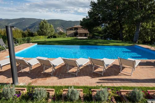 una piscina con sillas y una casa en el fondo en Casale Nasca, en Castelraimondo