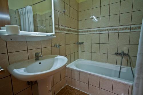 Grand Hotel Loutraki في لوتراكي: حمام مع حوض وحوض استحمام