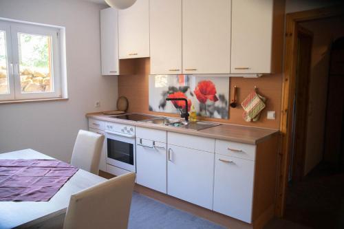 a kitchen with white cabinets and a sink and a table at Sweet Home in Gedern