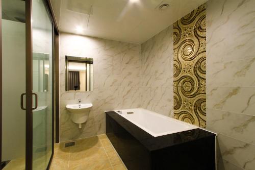 a bathroom with a sink and a tub and a toilet at The King Hotel in Busan