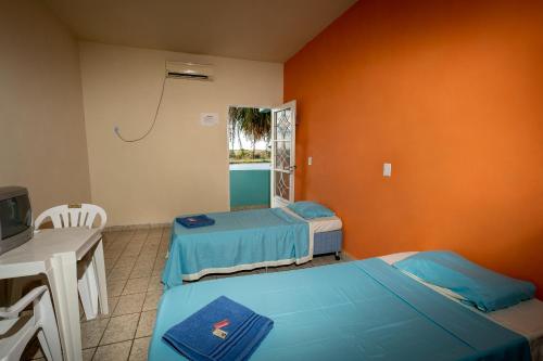 LadárioにあるPousada Pantanalのベッド2台、テーブル、テレビが備わる客室です。