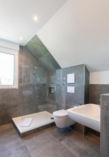 a bathroom with a shower and a sink and a toilet at Ferienwohnungen Der Loewen in Hagnau