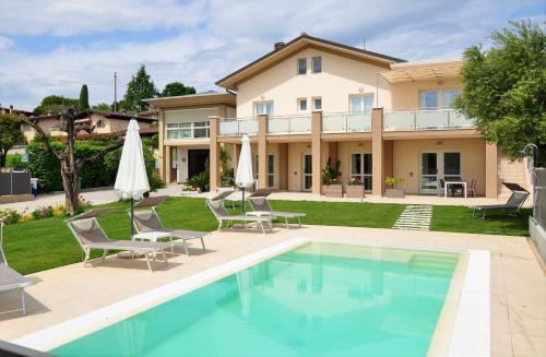 una casa con piscina, sillas y una casa en Garda Bloom Holiday Apartments, en Padenghe sul Garda