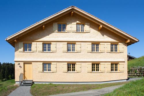 a large wooden house with windows on a hill at UNSER VORSÄSS - Geißkopf in Schwarzenberg im Bregenzerwald