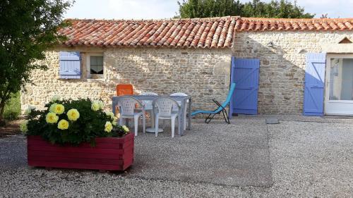 a table and chairs in front of a building with blue doors at La maison neuve in Fontaines