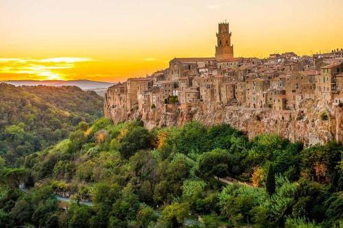a town on top of a mountain at sunset at La Casa all'Oliveto in Pitigliano