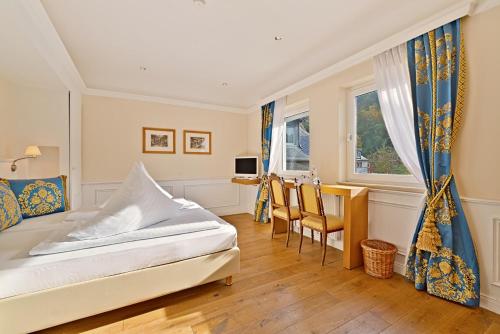 a bedroom with a bed and a table and chairs at Hotel Weinberg-Schlößchen in Oberheimbach